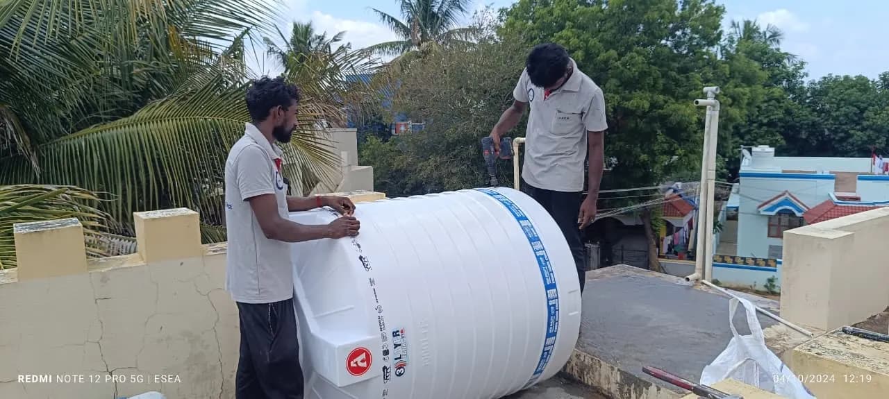 Two ESEA technicians installing a 1000 litre water tank on a rooftop
